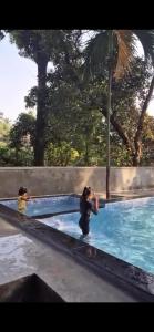 a woman taking a picture of a child in a swimming pool at Deepdaya Cottage in Alibag +21 photos
