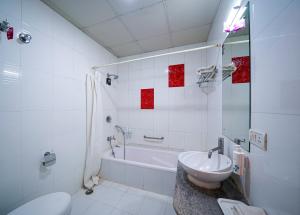 Un baño con bañera, lavabo e inodoro. en Olive Zip Rest House Road by Embassy Group, en Bangalore