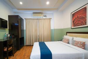 Un dormitorio con cama, escritorio y televisión. en Olive Zip Rest House Road by Embassy Group, en Bangalore