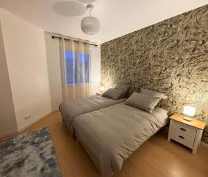 a bedroom with a bed and a stone wall at Maison cosy avec SPA privatif à 13 min du Futuroscope in Beaumont