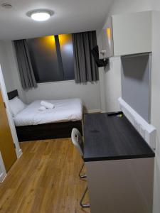 ein kleines Zimmer mit einem Bett und einem Schreibtisch. in der Unterkunft Modern Studio Apartment in Central Newcastle in Central Station