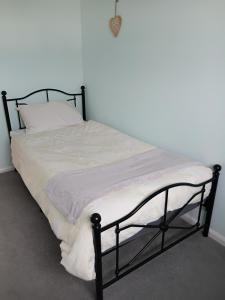 ein Bett mit schwarzem Rahmen und weißem Kissen in der Unterkunft Homely in Matson + 8 Fotos