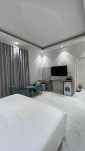 a white bedroom with a large bed and a tv at غرفه - واڤا in Tabuk