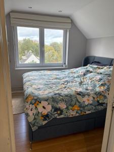 a bedroom with a bed with a floral comforter and a window at A 15 min de l'entrée de Bruxelles in Rixensart