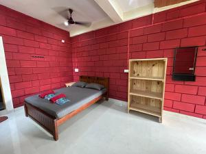 - une chambre avec un mur en briques rouges et un lit dans l'établissement Cocopelli Guest House, à Gokarna