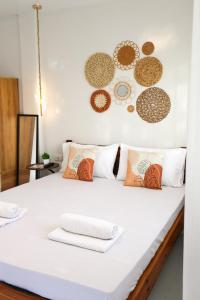 a white bed with pillows and plates on the wall at Felicitas Extension Room in General Luna