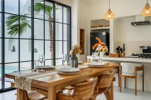 a dining room with a wooden table and a kitchen at Tanahlot Beachview Rooftop Villa in Tanah Lot