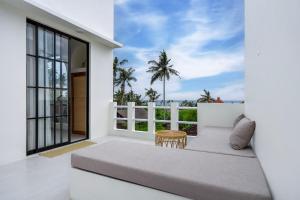 a balcony with a bed and a view of the ocean at Tanahlot Beachview Rooftop Villa in Tanah Lot