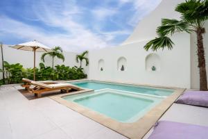 a swimming pool with a bench and an umbrella at Tanahlot Beachview Rooftop Villa in Tanah Lot