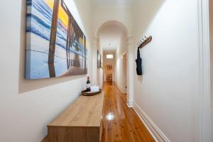 a hallway with paintings on the walls and a wooden floor at The Arches- Beautiful 3-Bedroom Family Stay Near Adelaide Oval, City Events and Amazing Dining in North Adelaide