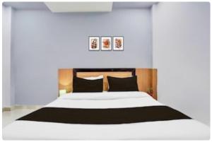 um quarto com uma grande cama branca com almofadas pretas em Collection O High Court Lucknow em Vibhuti Khand