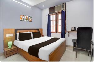 um quarto com uma cama, uma cadeira e uma janela em Collection O High Court Lucknow em Vibhuti Khand