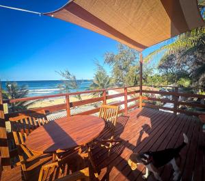 a table and chairs on a deck with the beach at Índico Breeze in Praia do Tofo