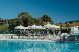 a pool with white umbrellas and chairs next to the water at Green Garden Village con piscina, spiaggia riservata e parcheggio in Sirolo