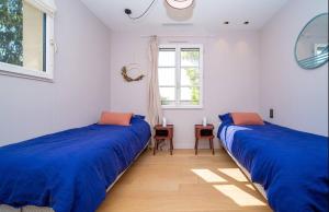 zwei Betten in einem weißen Zimmer mit blauen Laken in der Unterkunft Villa Violette in Tourrettes-sur-Loup