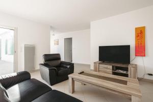 ein Wohnzimmer mit einem Sofa, einem TV und einem Stuhl in der Unterkunft Villa Du Chai in Sainte-Marie-de-Ré