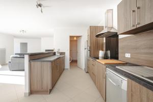 eine Küche mit Holzschränken und einer Arbeitsplatte in der Unterkunft Villa Du Chai in Sainte-Marie-de-Ré