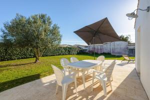 ein Tisch und Stühle mit einem Sonnenschirm auf einer Terrasse in der Unterkunft Villa Du Chai in Sainte-Marie-de-Ré