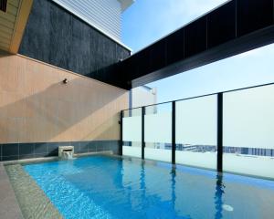 a swimming pool in a building with large windows at Candeo Hotels Hiroshima Hatchobori in Hiroshima
