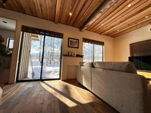 a living room with a couch and a sliding glass door at The Misorano Cottage in Hakuba
