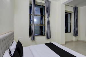 a bedroom with a bed and two windows at Hotel O Arena in Bhilai