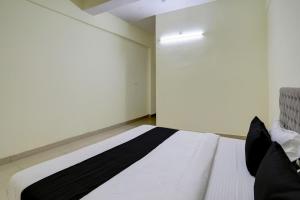 a bedroom with a white bed with black pillows at Hotel O Arena in Bhilai