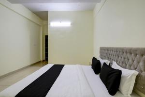 a bedroom with a large white bed with black pillows at Hotel O Arena in Bhilai