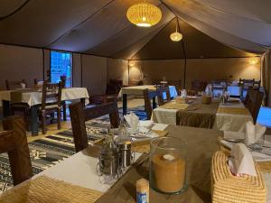 une salle à manger avec des tables et des chaises dans une tente dans l'établissement Merzouga Majestic Camp, à Merzouga