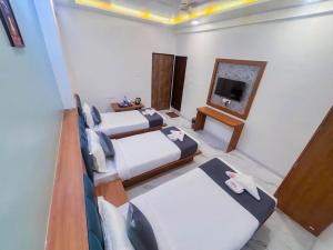 浦那Sunrise Comfort Rooms - International Tech Park Kharadi Highway的有三张床和一台电视的酒店房间