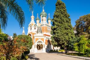 尼斯The cozy corner of Amelie的公园里的一座教堂，旁边有一棵棕榈树