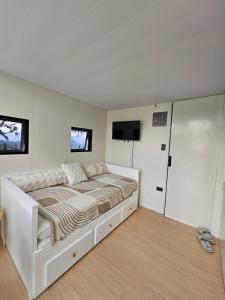 a white bedroom with a bed and a flat screen tv at Banaue Glass Cabins in Banaue