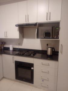 a kitchen with white cabinets and a stove and microwave at Amos in Gaborone