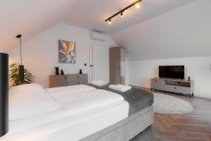 Zamkowy Zakątek - Luksusowe domki z jacuzzi في Nowy Wiśnicz: غرفة نوم بيضاء مع سرير كبير وتلفزيون بشاشة مسطحة