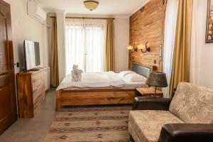 Valevtsi Mount Lodge - 365 days hot outdoor pool - في Valevtsi: غرفة نوم بها سرير وأريكة وتلفزيون