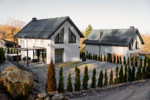 Zamkowy Zakątek - Luksusowe domki z jacuzzi في Nowy Wiśnicz: بيت أبيض بسقف أسود