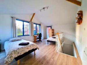 une chambre avec un lit, un bureau et des fenêtres dans l'établissement Gîte de l'Ecrin de l'Andelle - Un écrin de nature entre rivière et forêt, à Morville-sur-Andelle
