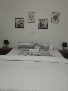 La Villa Moris, meublée et bien située في ليبرفيل: سرير ابيض بأربع صور على الحائط