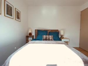 una camera da letto con un letto grande con cuscini blu di Le 5 ter - Cozy, quiet accommodation a Baud