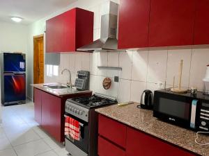 La Villa Moris, meublée et bien située في ليبرفيل: مطبخ بدولاب احمر وفرن فوق الفرن