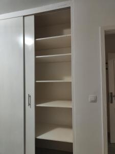 La Villa Moris, meublée et bien située في ليبرفيل: خزانة مع رفوف بيضاء وباب زجاجي +صورة واحدة