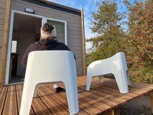 une personne assise sur une terrasse avec deux chaises blanches dans l'établissement Suite Hôtel, à Le Temple-sur-Lot