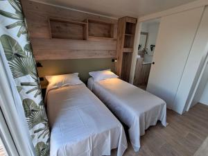 deux lits dans une petite pièce avec des draps blancs dans l'établissement Suite Hôtel, à Le Temple-sur-Lot 1 autre photo