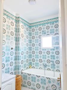 米多恩Villa Djerba Tourist Area的浴室贴着蓝白相间的壁纸，里面有个浴缸。