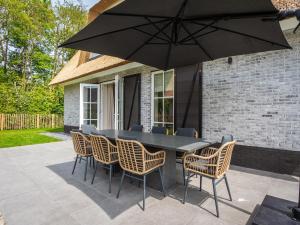 une table avec des chaises et un parasol sur une terrasse dans l'établissement Pretty Holiday Home in De Koog Texel with Garden, à Westermient