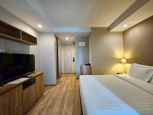 a hotel room with a bed and a flat screen tv at Baan Tanwa - MRT Ratchadapisek Exit 1 or 2 in Bangkok