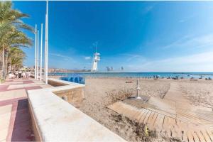 a sandy beach with a lighthouse in the distance at Apartamento en 1ª línea de playa con parking privado in El Campello +4 photos
