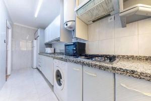a white kitchen with a washer and dryer in it at Apartamento en 1ª línea de playa con parking privado in El Campello