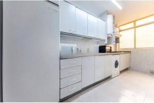 a kitchen with white cabinets and a washer and dryer at Apartamento en 1ª línea de playa con parking privado in El Campello