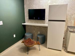 eine Küche mit einem TV, einem Tisch und einem Kühlschrank in der Unterkunft Vila Chalés in Mucuri