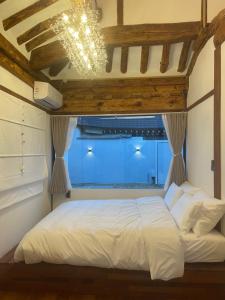 a bedroom with a white bed with a window at Hanok Hyeyum in Jeonju